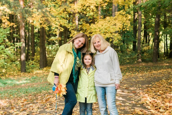 Portrét tří generací šťastné krásné ženy dívající se do kamery, objímající a usmívající se v podzimní přírodě — Stock fotografie