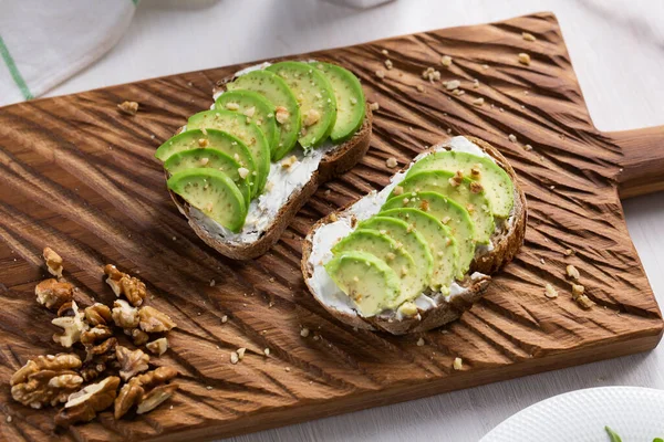 Нарезанный авокадо на хлебе с орехами. Концепция завтрака и здорового питания. — стоковое фото