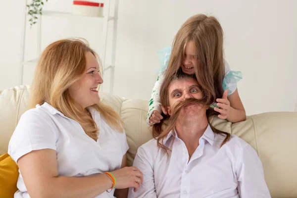 Die Familie sitzt auf dem Sofa im Wohnzimmer. Tochter hat Verletzung an der Hand, aber sie ist glücklich, mit ihrer Familie zusammen zu sein. — Stockfoto