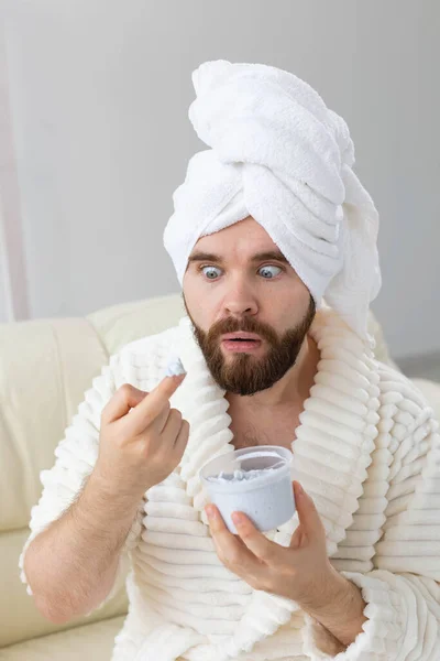 Homem engraçado aplicando creme eficaz em sua pele facial. Spa em casa, corpo e cuidados com a pele para o conceito masculino. — Fotografia de Stock