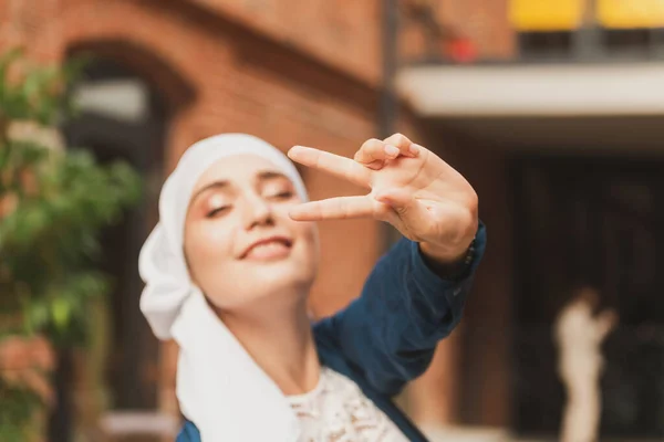 Retrato da jovem mulher muçulmana usando lenço de cabeça hijab na cidade enquanto olha para a câmera. Close-up rosto de mulher alegre coberto com lenço de cabeça sorrindo ao ar livre. Menina islâmica ao ar livre. — Fotografia de Stock