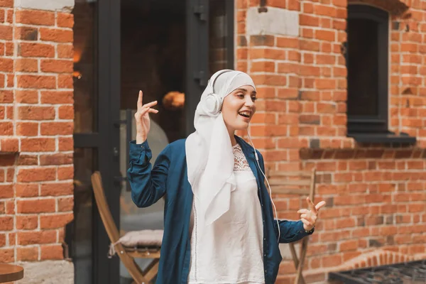 Retrato da jovem mulher muçulmana árabe ouvindo música com fone de ouvido e dança. Feminismo, independência da mulher e conceito de lazer. — Fotografia de Stock
