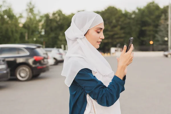 Μουσουλμάνα νεαρή γυναίκα που φοράει μαντήλι κεφαλής χιτζάμπ στην πόλη στέλνει μηνύματα στο κινητό — Φωτογραφία Αρχείου
