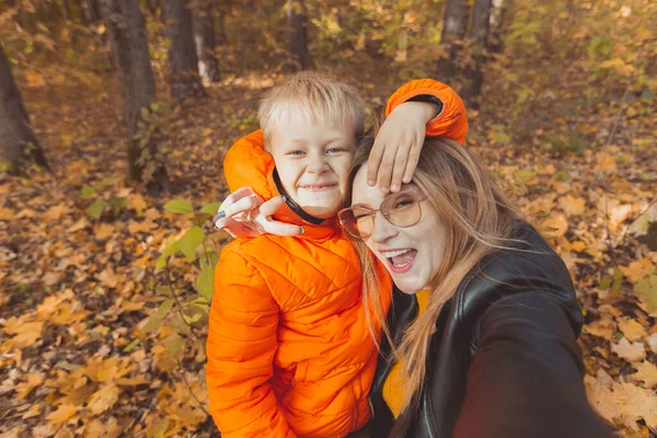 Hijo y madre se están tomando selfie en cámara en el parque de otoño. Concepto de temporada monoparental, de ocio y otoño. —  Fotos de Stock
