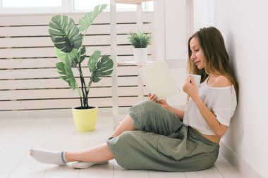 Genç bir kadın evde fotoğraf albümüne bakıyor ve çay içiyor. Anılar ve eğlence konsepti.