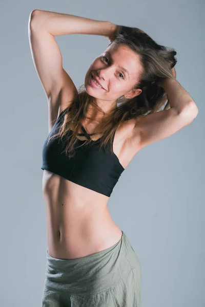 Фітнес дівчина зі спортивним тілом позує в студії на сірому фоні. Фітнес усміхнена модель в спортивному одязі. Втрата ваги. Здоровий спосіб життя. Спортивні здорові жінки . — стокове фото