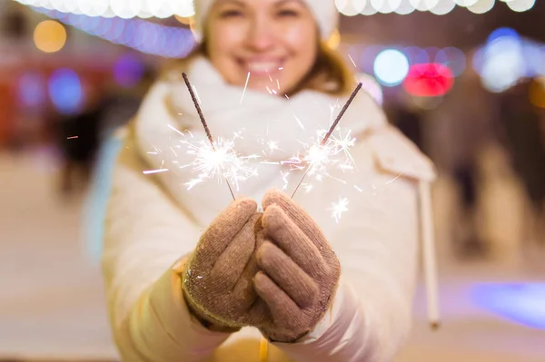 雪の背景の上に輝く屋外を保持冬のニットの服を着て笑顔若い女性。クリスマス休暇. — ストック写真