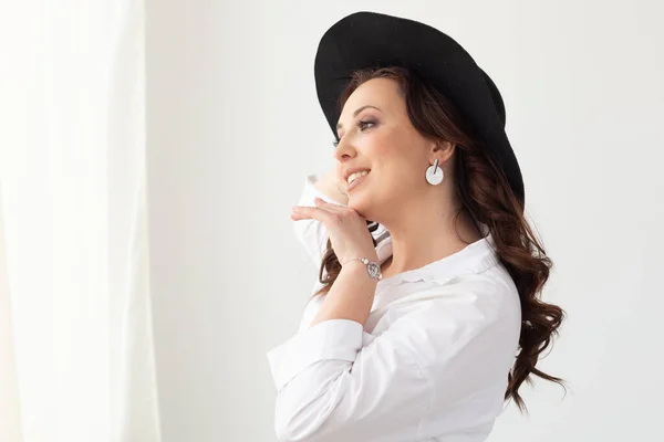 Retrato de uma bela mulher graciosa em chapéu elegante com uma aba larga em fundo claro com espaço de cópia. Conceito de beleza e moda. Espaço de cópia — Fotografia de Stock