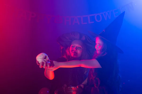 Zwei Halloween-Hexen basteln einen Zaubertrank und zaubern in der Halloween-Nacht. Magie, Urlaub und mystisches Konzept. — Stockfoto