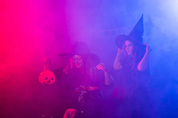 Dos brujas de Halloween haciendo una poción y conjurando en la noche de Halloween. Magia, vacaciones y concepto místico. — Foto de Stock