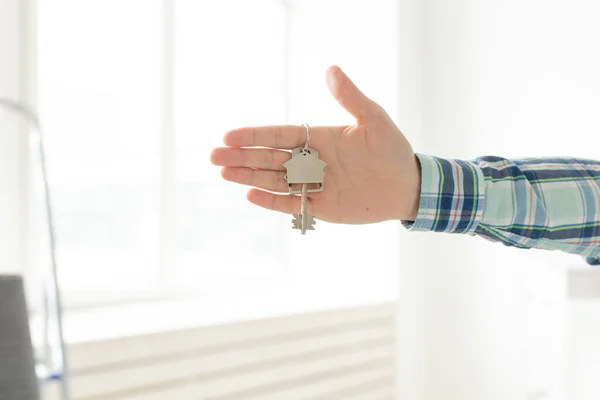 Holding house keys on house shaped keychain in a new home. Mortgage and home loan concept. — Stock Photo, Image