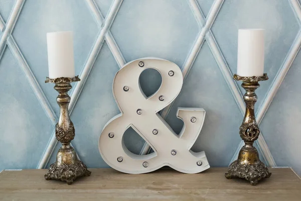 Ampersand sign on wood table with candles. Interior and furniture concept. — Stock Photo, Image