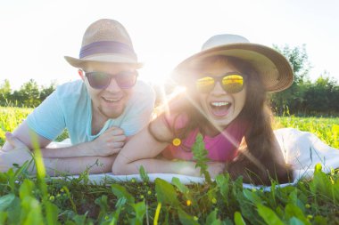Çimlerin üzerinde yatan komik genç bir çift. Nişan ve açık hava portresi konsepti.