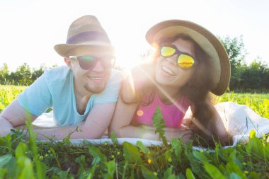 Kameraya bakarak ve gülümseyen otların arasında yatarak genç bir çift ile eğlenceli ve sevgi kavramı.