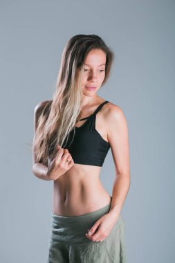 Spor vücutlu spor kızı gri arka planda stüdyoda poz veriyor. Spor giyim sektöründe spor kıyafetli, gülümseyen bir model. Kilo kaybı. Sağlıklı bir yaşam tarzı. Sportif, sağlıklı kadın..