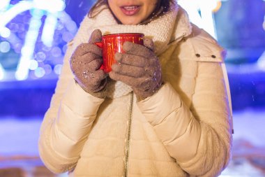 Kış boyunca ayakta duran kız. Arka planda kar yağıyordu. Sıcak ceket şapkası takıyor, çay ve sıcak çay içiyordu..