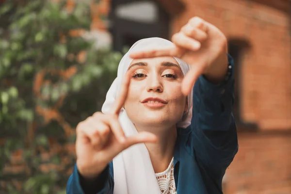 Porträt eines jungen muslimischen Mädchens, das mit den Fingern im Freien einen Kamerarahmen herstellt. — Stockfoto