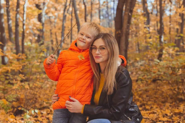 Anne sonbahar parkında yürürken çocuğuna sarılıyor. Sonbahar sezonu ve tek ebeveyn kavramı. — Stok fotoğraf