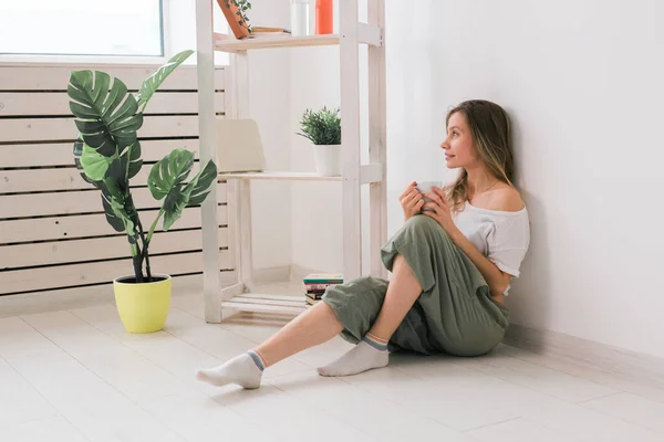 Ragazza sognante seduta sul pavimento a casa e bere il tè dalla tazza. — Foto Stock