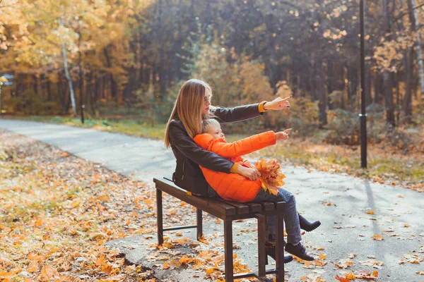 Bekar anne ve çocuk sonbaharda parkta bankta otururlar. Sonbahar sezonu ve aile kavramı. — Stok fotoğraf