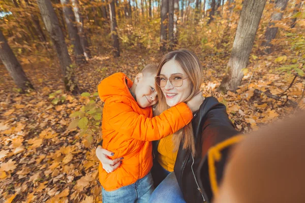 Syn i matka robią selfie przed kamerą w jesiennym parku. Koncepcja samotnego rodzica, spędzania wolnego czasu i jesieni. — Zdjęcie stockowe