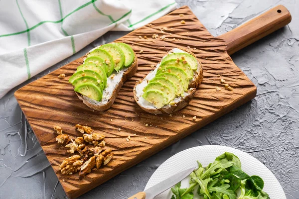 Сэндвич с авокадо на темном ржаном хлебе, сделанный из свежих нарезанных авокадо сверху. Концепция. — стоковое фото