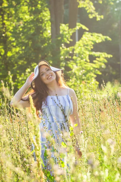 Jonge vrouw wandelen tussen wilde bloemen op zonnige zomerdag. Concept van de vreugde van het communiceren met de zomerse natuur — Stockfoto