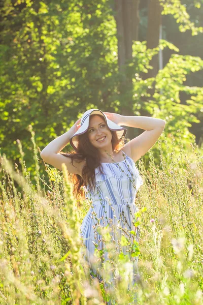 Молодая женщина гуляет среди полевых цветов в солнечный летний день. Концепция радости общения с летней природой — стоковое фото