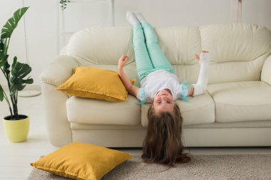 Kırık bileği ya da kolu olan bir çocuk gülümsüyor ve kanepede eğleniyor. Pozitif tutum, iyileşme ve çocuk konsepti.