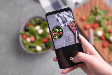 Mozarella ve cep telefonu kamerasında ıspanak ile taze sebze salatası çeken bir adam. Yemek pişirme, blog yazma ve sağlıklı beslenme kavramı.