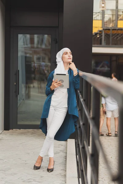 Портрет арабской студентки, держащей планшет. Арабская деловая женщина в хиджабе держит планшет на улице. Женщина одета в хиджаб — стоковое фото