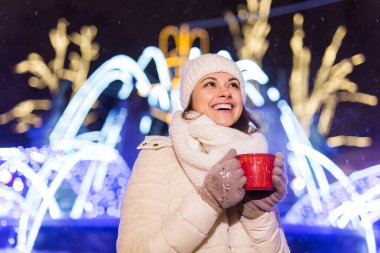 Kış boyunca ayakta duran kız. Arka planda kar yağıyordu. Sıcak ceket şapkası takıyor, çay ve sıcak çay içiyordu..