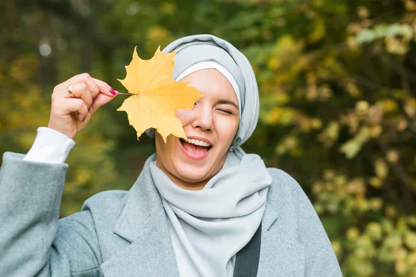 Muslimische Frau im Herbst mit Ahornblatt im Freien bei sonnigem Wetter. Schöne Araberin trägt Hijab-Mädchen im Herbst Park — Stockfoto