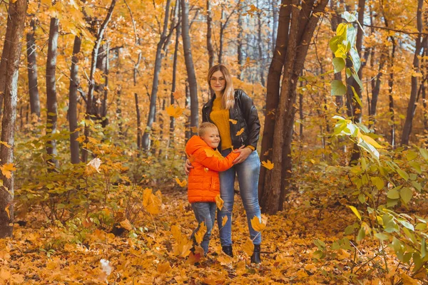 Madre abrazando a su hijo durante el paseo en el parque de otoño. Temporada de otoño y concepto de padre único. —  Fotos de Stock