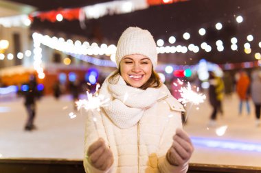 Elinde maytap tutan bir kız. Açık hava kış şehri arka planı, kar, kar taneleri.