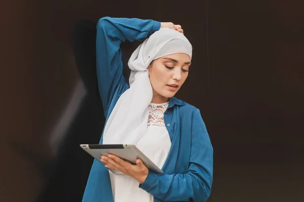 Retrato de uma estudante árabe segurando um tablet. Mulher de negócios árabe em hijab segurando um tablet na rua. Mulher está vestida com hijab — Fotografia de Stock