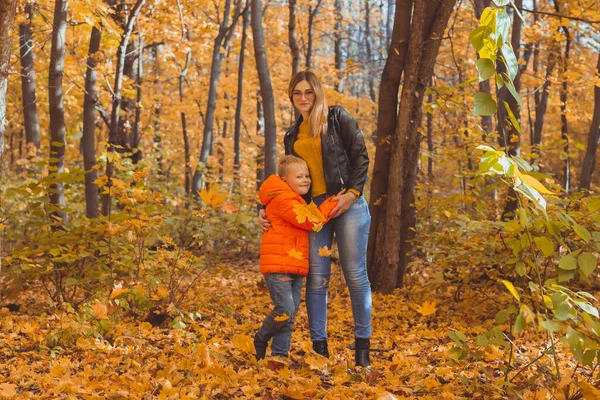 Mother hugging her child during walk in autumn park. Fall season and single parent concept. — Stock Photo, Image