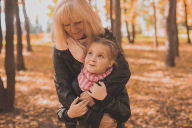 Büyükanne ve torunu sonbahar parkında. Nesil ve aile kavramı.
