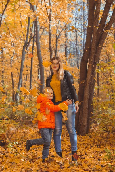 Mãe abraçando seu filho durante a caminhada no parque de outono. Temporada de outono e conceito de pai solteiro. — Fotografia de Stock