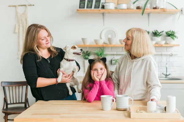 Bonne petite-fille et grand-mère et fille s'amuser avec Jack Russell terrier chien. Grand-mère embrasse son petit-enfant à la maison. Relation, famille et concept de trois générations. — Photo