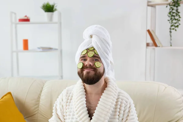 Hombre barbudo sosteniendo rodajas de pepino en la cara. Spa en el hogar, cuidado corporal y de la piel para el concepto masculino. —  Fotos de Stock