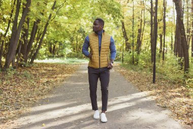 Afrikalı Amerikalı öğrenci sonbahar sezonunda parkta yürüyor.