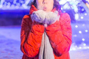 Noel dekorasyon ışıkları sokağında eğlenen bir kız. Açık havada şık örgü örüp ceket giyen mutlu, genç bir kadın. Model gülüşü. Kış Harikalar Diyarı Sahnesi, Yeni Yıl Partisi.