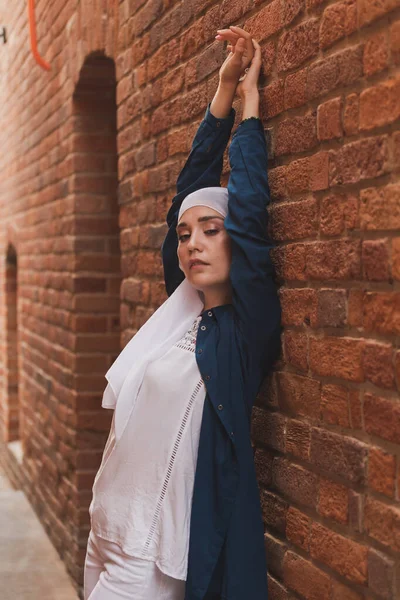 히잡을 입고 평범 한 옷차림을 하고 도시 배경에서 포즈를 취하는 아름다운 이슬람 여성 모델 — 스톡 사진