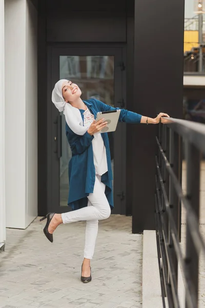 Porträtt av en arabisk student som håller i en surfplatta. Arabisk affärskvinna i hijab som håller en surfplatta på gatan. Kvinnan är klädd i hijab — Stockfoto