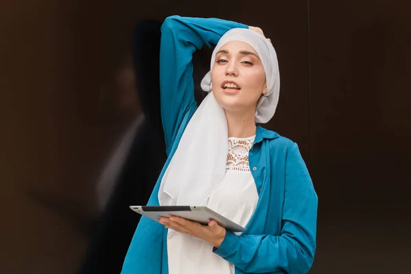 Νεαρή Ασιάτισσα μουσουλμάνα γυναίκα στο κεφάλι φουλάρι χαμόγελο με κινητό δισκίο — Φωτογραφία Αρχείου