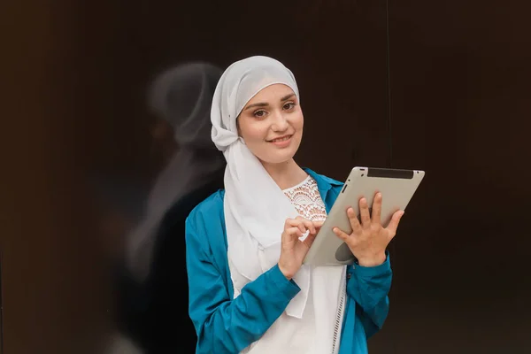 Mulheres de negócios asiáticas bonitas vestindo hijab usando seu tablet ao ar livre. — Fotografia de Stock