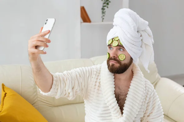 Hombre barbudo sosteniendo rodajas de pepino en la cara. Spa en el hogar, cuidado corporal y de la piel para el concepto masculino. —  Fotos de Stock