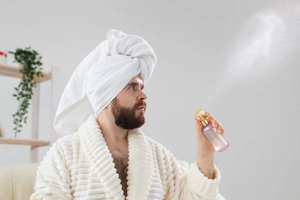 Homem barbudo com toalha de banho na cabeça aplicando tratamento de água spray no rosto. Spa, corpo e cuidados com a pele para o conceito de homem. — Fotografia de Stock