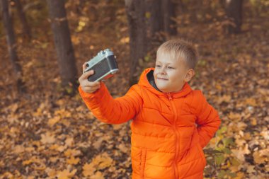 Sonbaharda parkta selfie çeken bir çocuk. Sonbahar ve eğlence konsepti.